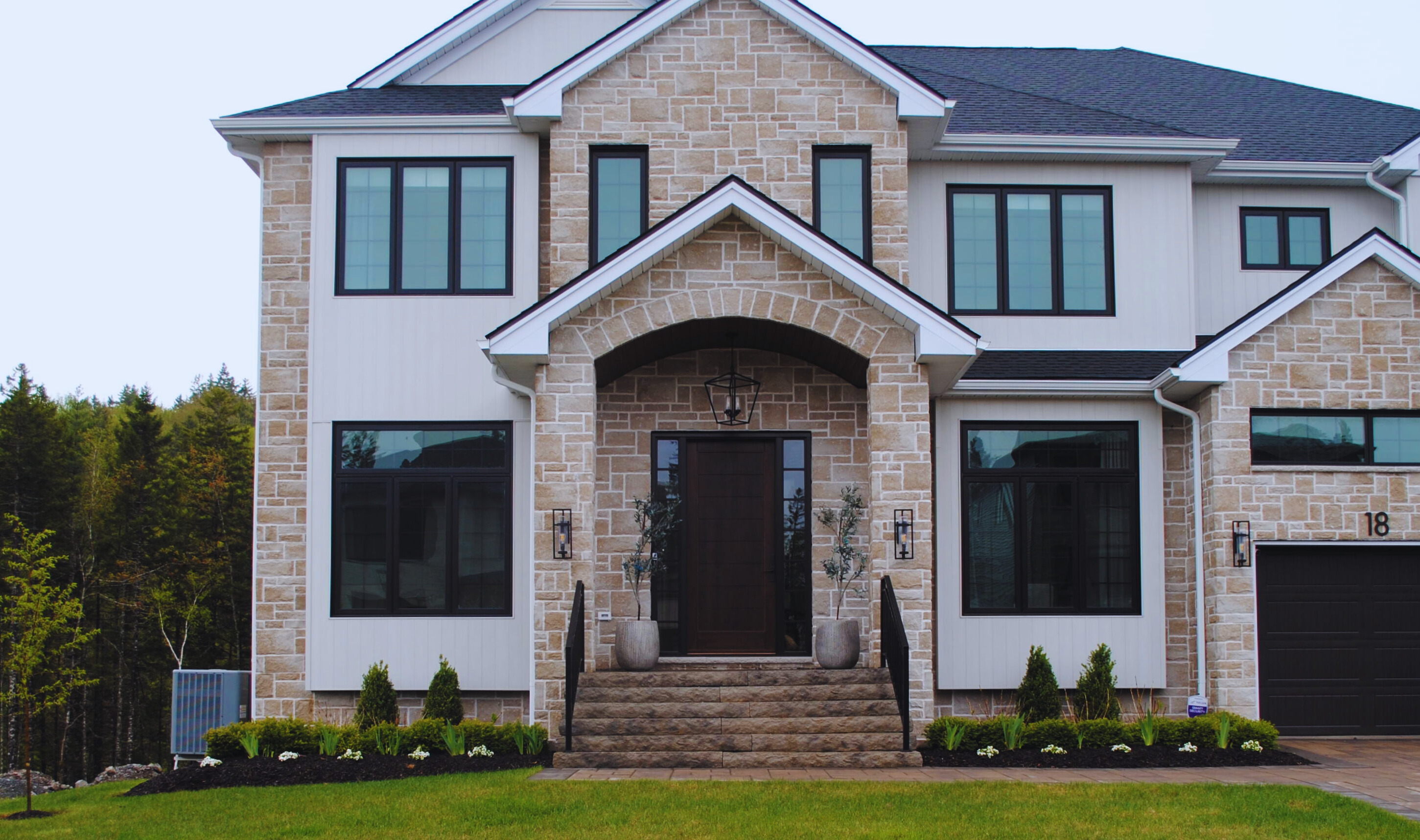 Luxury stone home front entrance with professional landscaping, black mulch beds and manicured shrubs — Dunbrack's Outdoor Services, Halifax NS