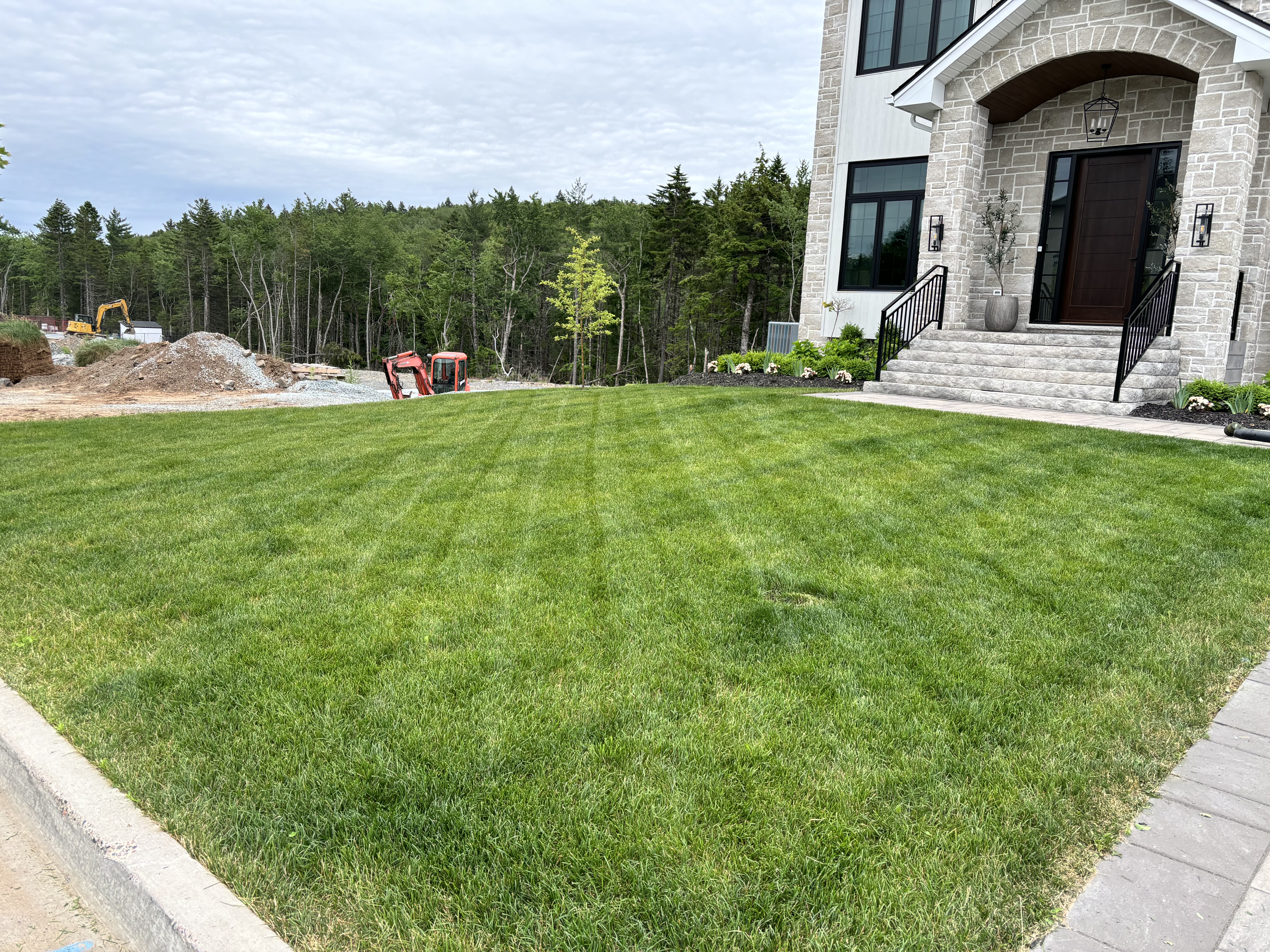 Freshly striped lawn at new stone home with professional front bed landscaping — Dunbrack's Outdoor Services, Halifax NS