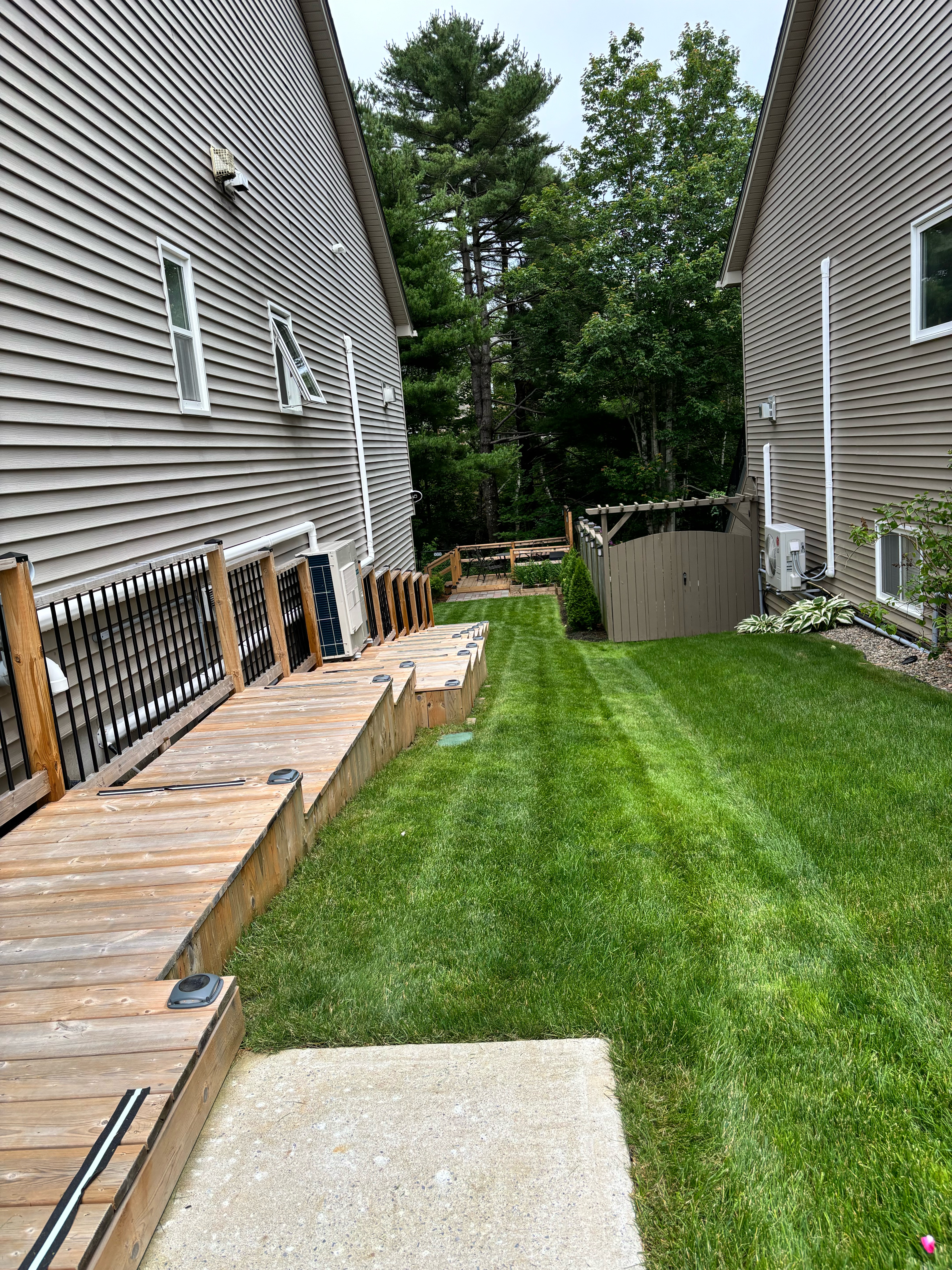 Neatly mowed backyard between townhomes with wooden deck — lawn care by Dunbrack's Outdoor Services, Halifax NS