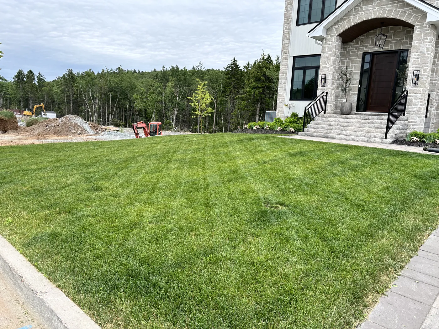 Freshly striped lawn at new stone home with professional front bed landscaping — Dunbrack's Outdoor Services, Halifax NS